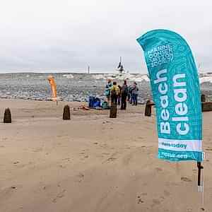 A beach with a flag in the foreground that reads "Marine Conservation Society Beach Clean"