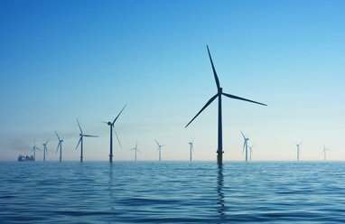Wind turbines in water at Rampion Offshore Wind Farm, United Kingdom, with blue skies above the water